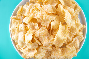 Sfrappole or chiachiere or angel wings on a bright blue background. Italian Carnival and TYPICAL food. Traditional sweet crisp pastry deep-fried and sprinkled with powdered sugar. 