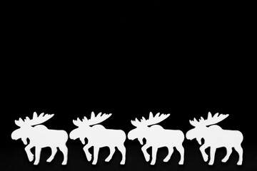 White wooden reindeer on a black background,
christmas silhouette. Top view, copy space.