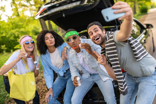 Group of friends making selfie in the forest while sitting on the car boot - Powered by Adobe