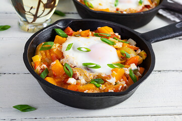 Shakshouka in frying pan. Fried eggs with vegetables, tomato, pepper, pumpkin and onion