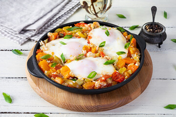 Shakshouka in frying pan. Fried eggs with vegetables, tomato, pepper, pumpkin and onion