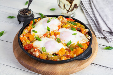 Shakshouka in frying pan. Fried eggs with vegetables, tomato, pepper, pumpkin and onion