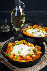 Shakshouka in frying pan. Fried eggs with vegetables, tomato, pepper, pumpkin and onion