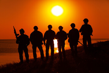 Army soldiers with rifles orange sunset silhouette