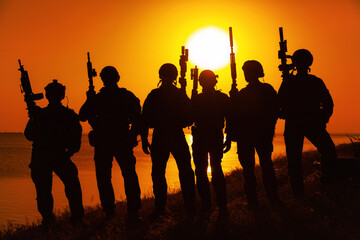 Army soldiers with rifles orange sunset silhouette