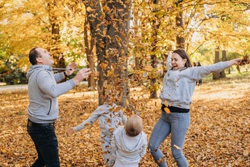 Portrait of a happy beautiful family having fun and throwing autumn leaves in the air. Happy...
