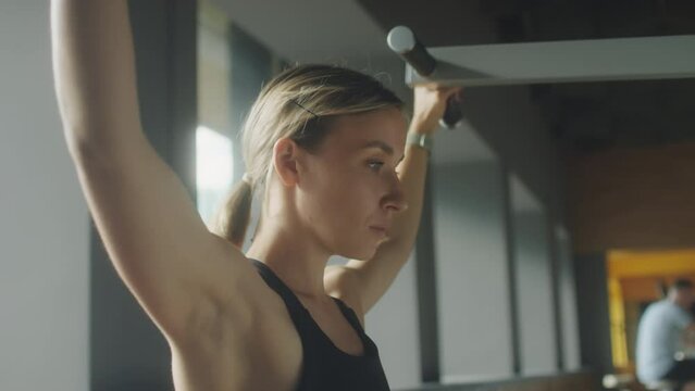 Chest up shot of strong woman using lat pulldown machine while training in gym