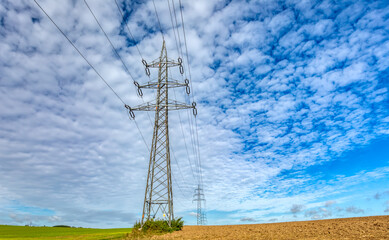 High voltage power lines in field against a blue sky. Autumn fall season, Europe Czech Republic