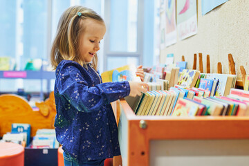 4 year old girl selecting a book in municipal library