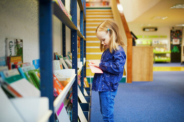 4 year old girl selecting a book in municipal library