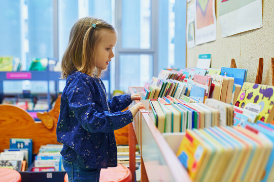 4 year old girl selecting a book in municipal library