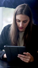 Portrait of a young woman browsing internet on tablet device. Vertical video of a girl using modern...