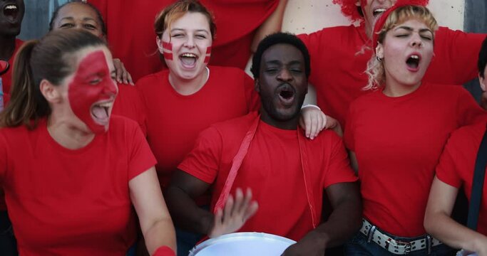 Multiracial red sport fans screaming while supporting their team - Football supporters having fun at competion event - World cup conceptconcept