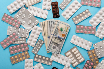 Different medical drugs and dollar currency notes on blue background