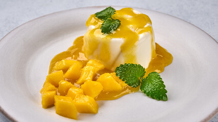 Panna cotta with natural vanilla pod, mango syrup and mint, high key. Panoramic view, close up