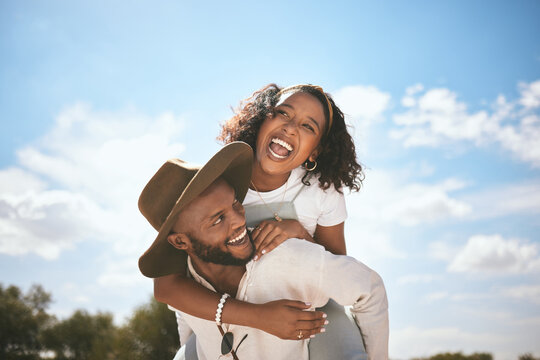 Piggyback, love and couple with smile on a date in nature together during summer. Happy, playful and African man and woman beeing funny, crazy and young in a green park or garden during spring