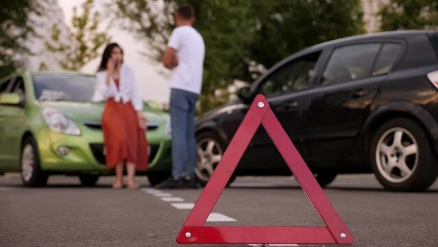 Red emergency stop triangle sign afore Destroyed car in car crash traffic accident on city road. Man driver looking on Smashed broken car in accident. Copy space.