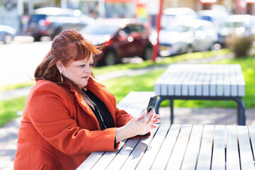 Woman with unsure neutral expression looking at mobile phone in park