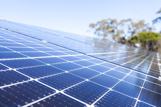 Rows of blue solar panels up to sky on roof of home