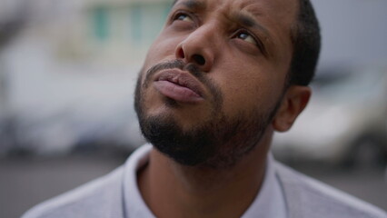 Fototapeta premium One anxious young African American man in distress closeup face. Portrait of a black person with worried preoccupied emotion
