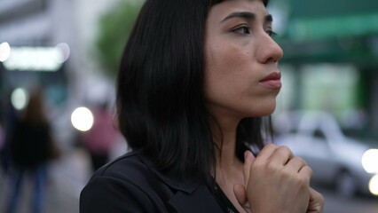 Stressed young hispanic woman standing in street feeling nervous rubbing hands in doubt and anxiety