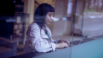 South American young woman thinking of an idea while working in front of laptop. A Brazilian adult...