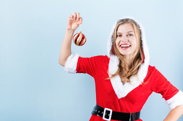 closeup of caucasian happy woman wearing santa clothes laughing holding christmas ball