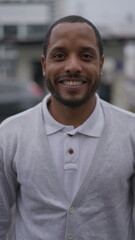 Portrait of a happy Brazilian African American young man smiling at camera standing in street looking at camera wearing polo shirt in Vertical Video SS