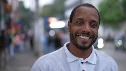 Portrait of a happy black man standing in street smiling at camera. African American person closeup face