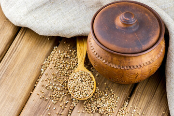 Top view of clay pot with wooden spoon full of buckwheat