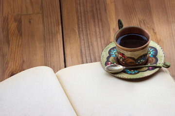 Top view of traditional Turkish copper cup of tea with blank old book on wooden table