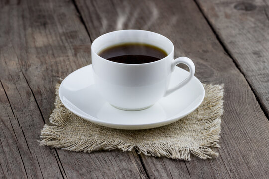 Top view of white cup of coffee on old wooden background