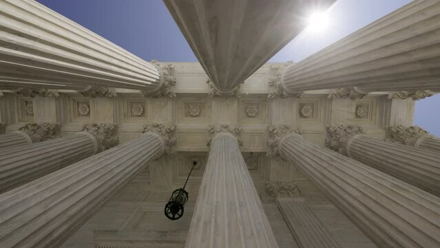 Low Angle View of the Sun Appearing Behind Columns of the Supreme Court
