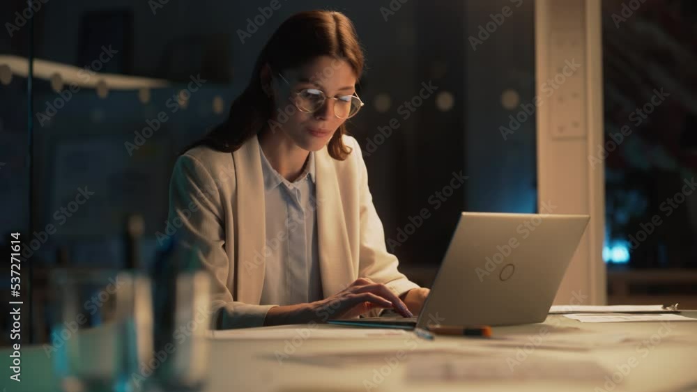 Poster stylish female working on laptop computer in a company office in the evening. young manager browsing