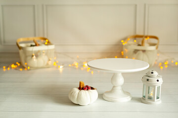 Festive white background with white pumpkins and a stand for sweets