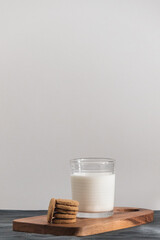 Minimalist picture of a milk glass and cookies with a light grey background for copy space. Breakfast concept.
