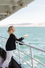 side view of woman in black sweater looking at sea from ferry boat crossing bosporus in istanbul.