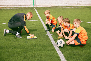 Junior soccer team training with football coach at sports stadium, outdoors. Concept of sport, competition, studying and achievements