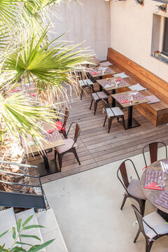 Terrasse de restaurant avec tables en ext&eacute;rieur et palmier