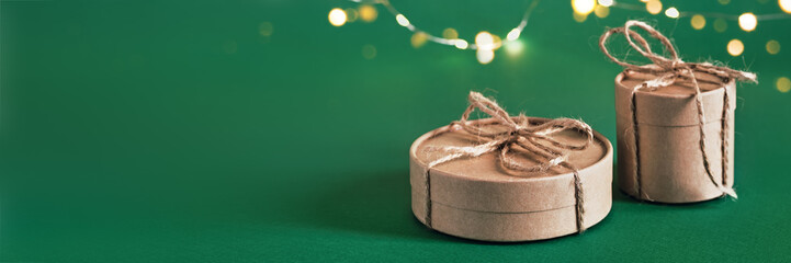 Christmas sustainable round gift boxes and shining garland on green banner. Christmas zero waste