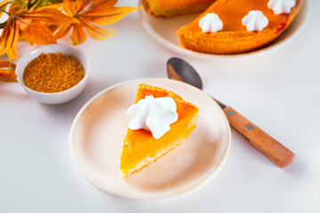 Slice of fresh baked traditional american homemade pumpkin pie decorating whipped cream for celebrating holidays