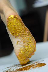 foot in gold.leg of a girl in sequins.foot close-up.sequins on the leg.naked sequins.women's shin