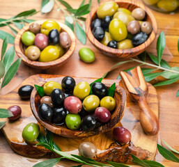 Kalamata, green and black olives in the wooden bowls on wooden table. Top view.
