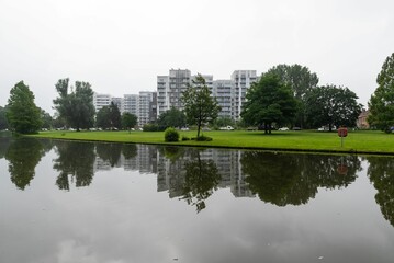 Kortrijk, West Flanders Region - Belgium -  The Raemdonck city park water pond with residential apartment blocks reflecting in the background.