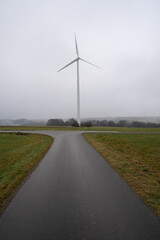 Fototapeta na wymiar Walkway in the landscape with a wind turbine in the distance on a foggy day in december 