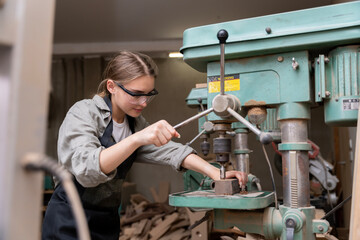 Portrait of a female carpenter using tools or machines for cutting, not drilling, wood to make furniture in a furniture factory. with modern tools