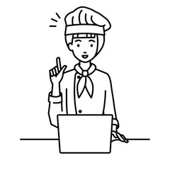 デスクで座ってPCを開いて何かひらめいた調理師の女性