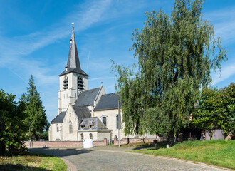 Fototapeta na wymiar Kobbegem, Flemish Brabant Region, Belgium - Paved road and catholic church of the village