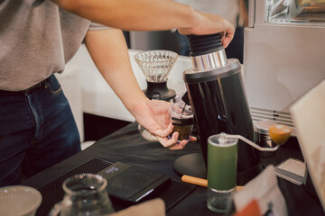 Barista grinding coffee beans in coffee shop.