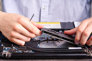 Fototapeta na wymiar Hands fixing motherboard of pc or laptop notebook close up in service. Laptop repair service. PC hardware upgrade and maintenance. Engineer fixing broken notebook.